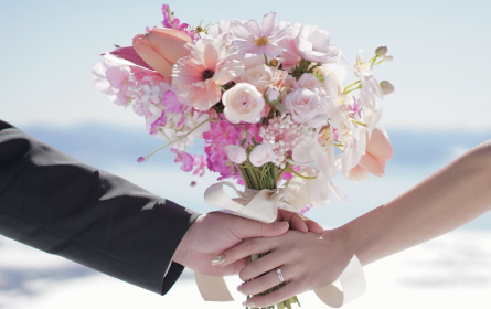 手をつなぎ花束を持つ男女