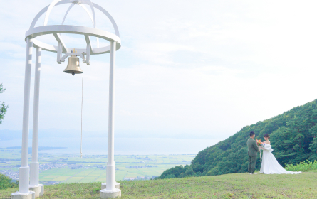 幸福の鐘と手をつなぎ花束を持つ男女